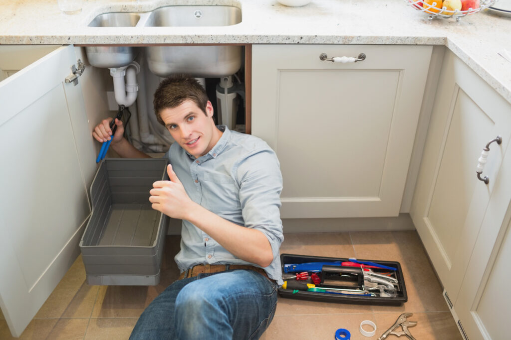 Man-fixing-kitchen-sink-giving-thumbs-up